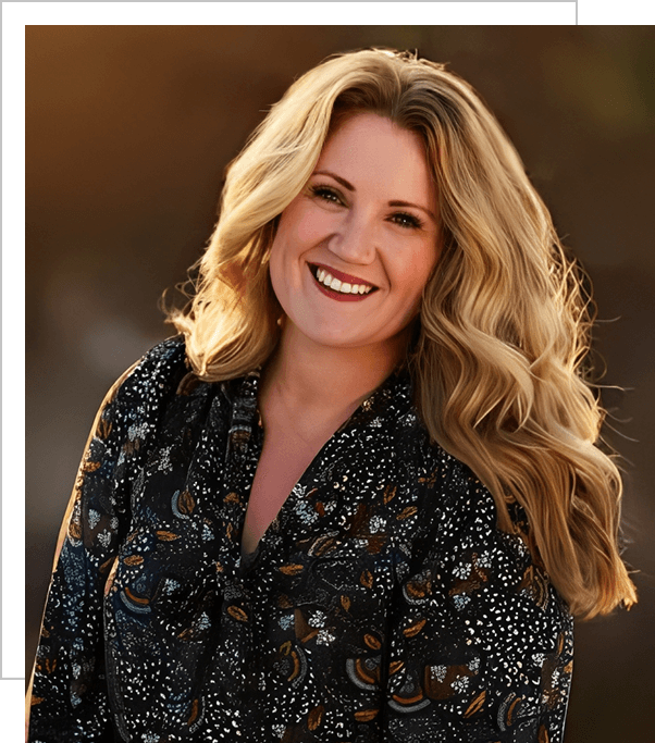 A woman with long blonde hair wearing a black and brown floral shirt.