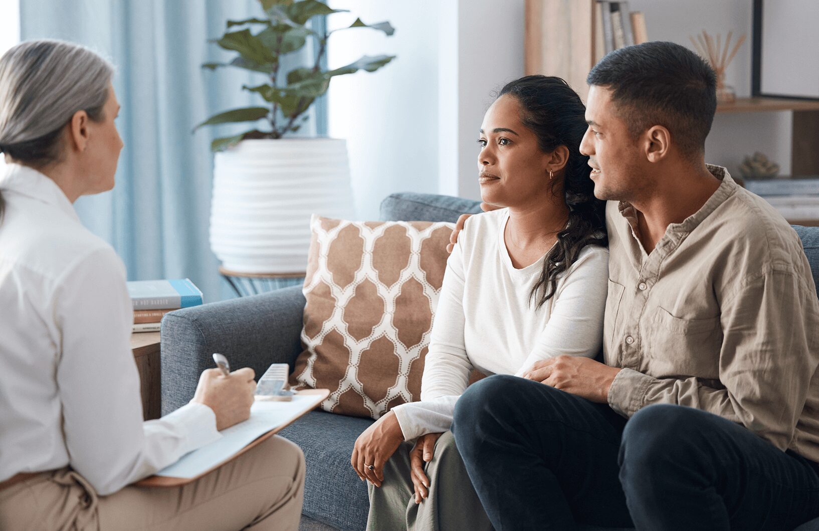 A man and woman sitting on the couch talking to someone.