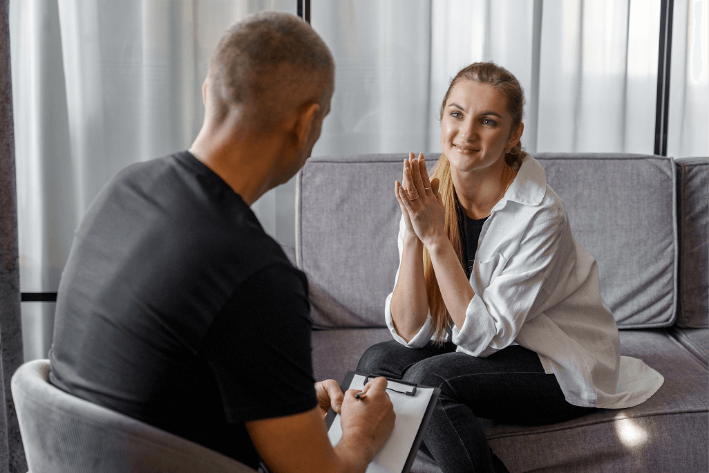 A man and woman sitting on a couch talking.