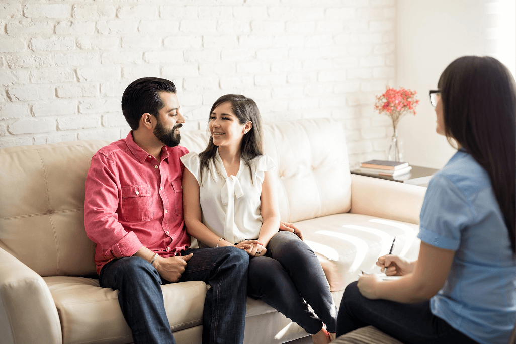 A man and woman sitting on the couch talking to two other people.