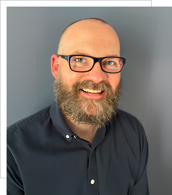 A man with a beard and glasses smiling for the camera.